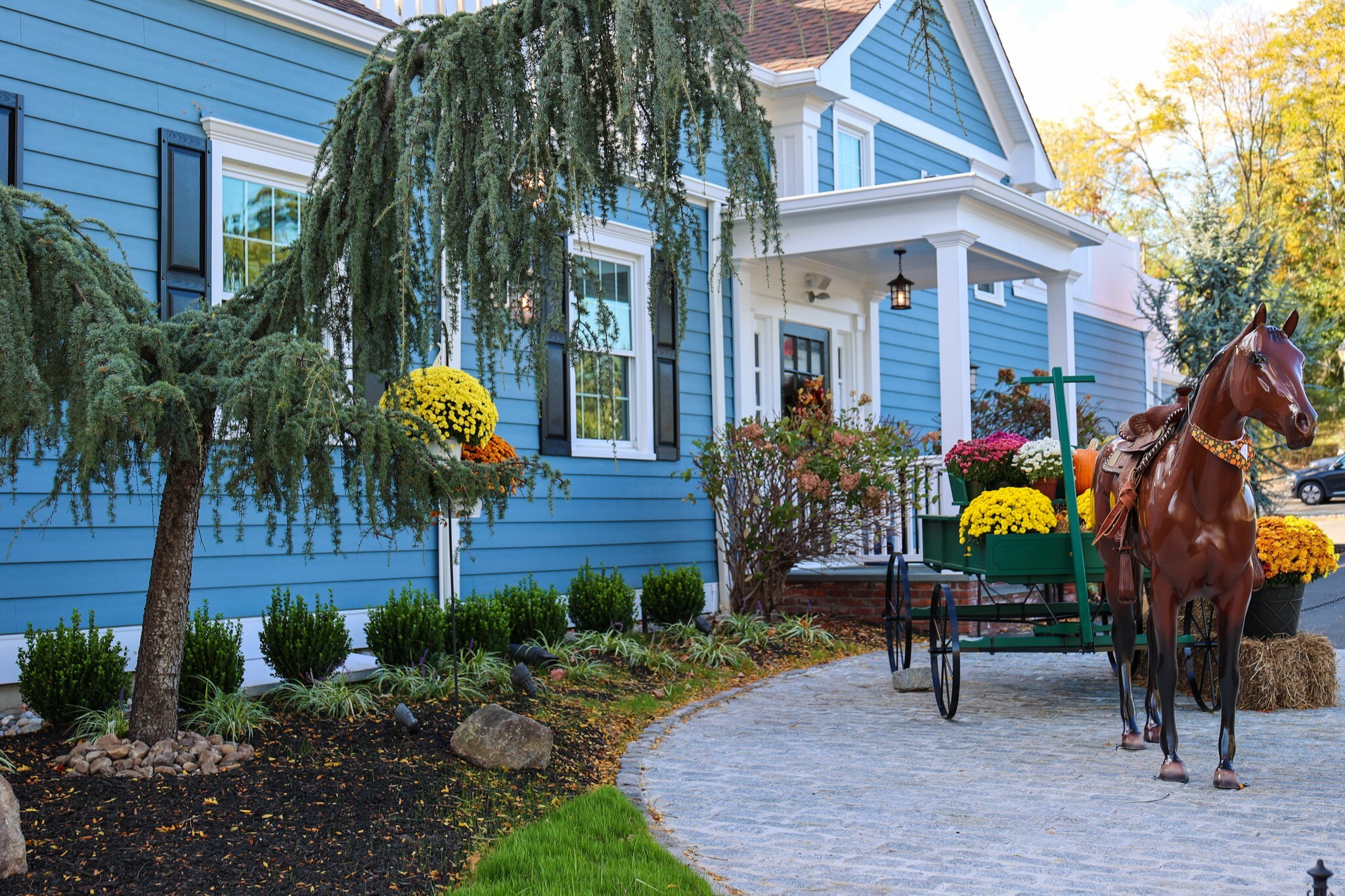 The front entrance of The Bedminster Tavern at 285 Main Street in Bedminster, New Jersey, with autumn flowers and a horse statue.